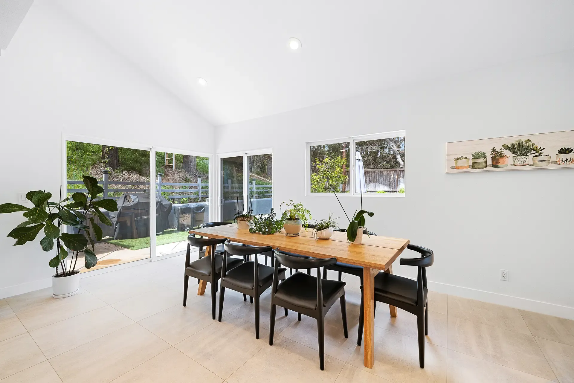 bright dining area with wood table, black chairs, and sliding glass doors to yard