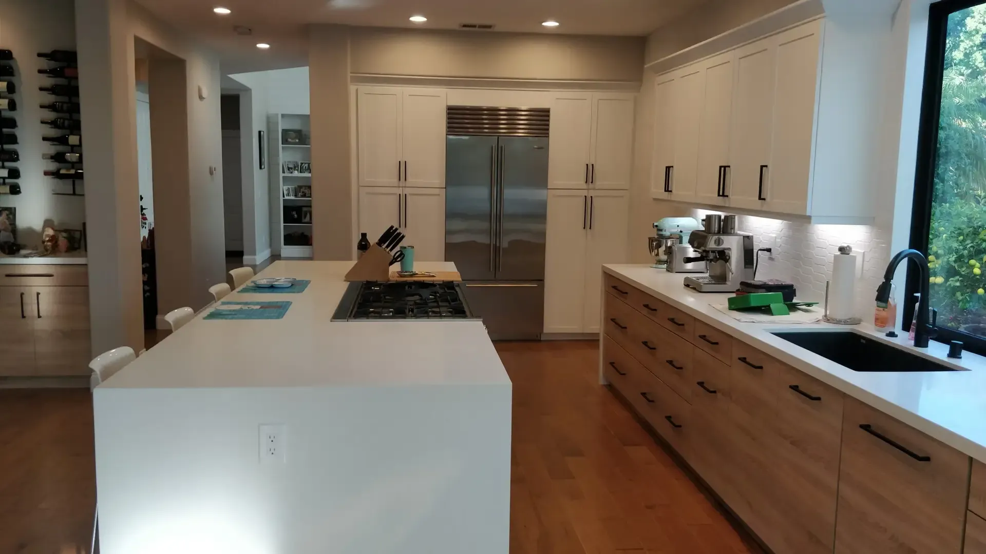 Bright kitchen with white island, gas cooktop and stainless paneled refrigerator