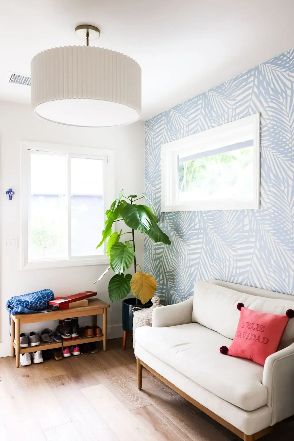 Bright sitting nook with blue palm-leaf wallpaper, neutral sofa and bench seating