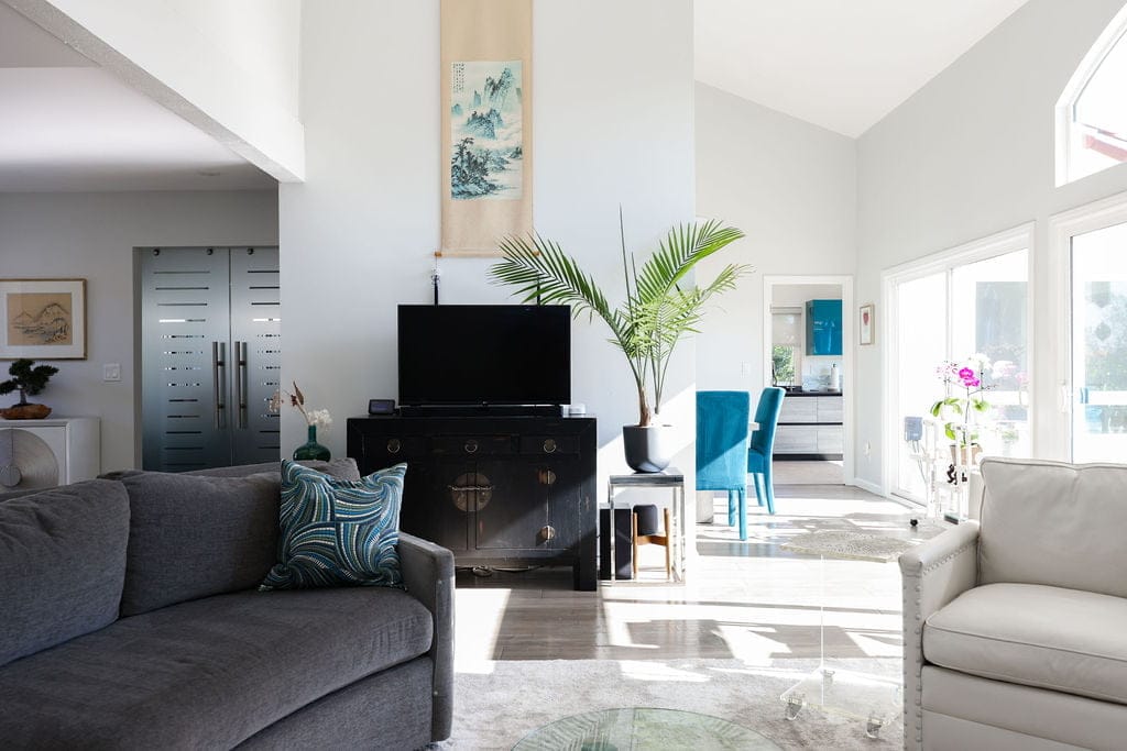 Bright vaulted living room with gray sofa, teal accents and wood flooring
