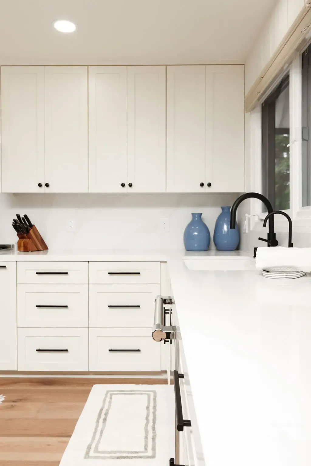 Bright white cabinets and waterfall quartz island with blue vase accents