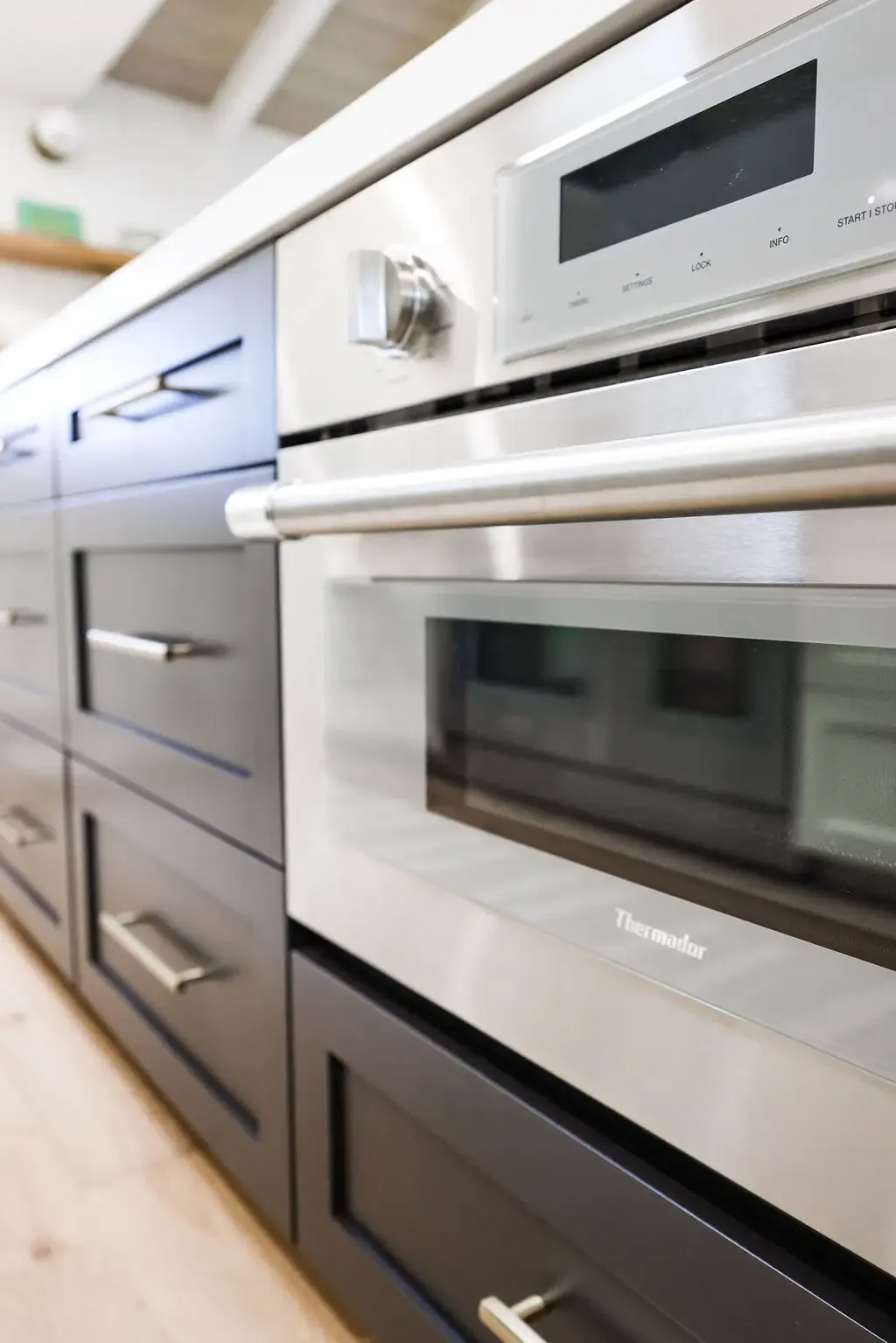 Built-in stainless wall ovens framed by deep navy shaker drawers