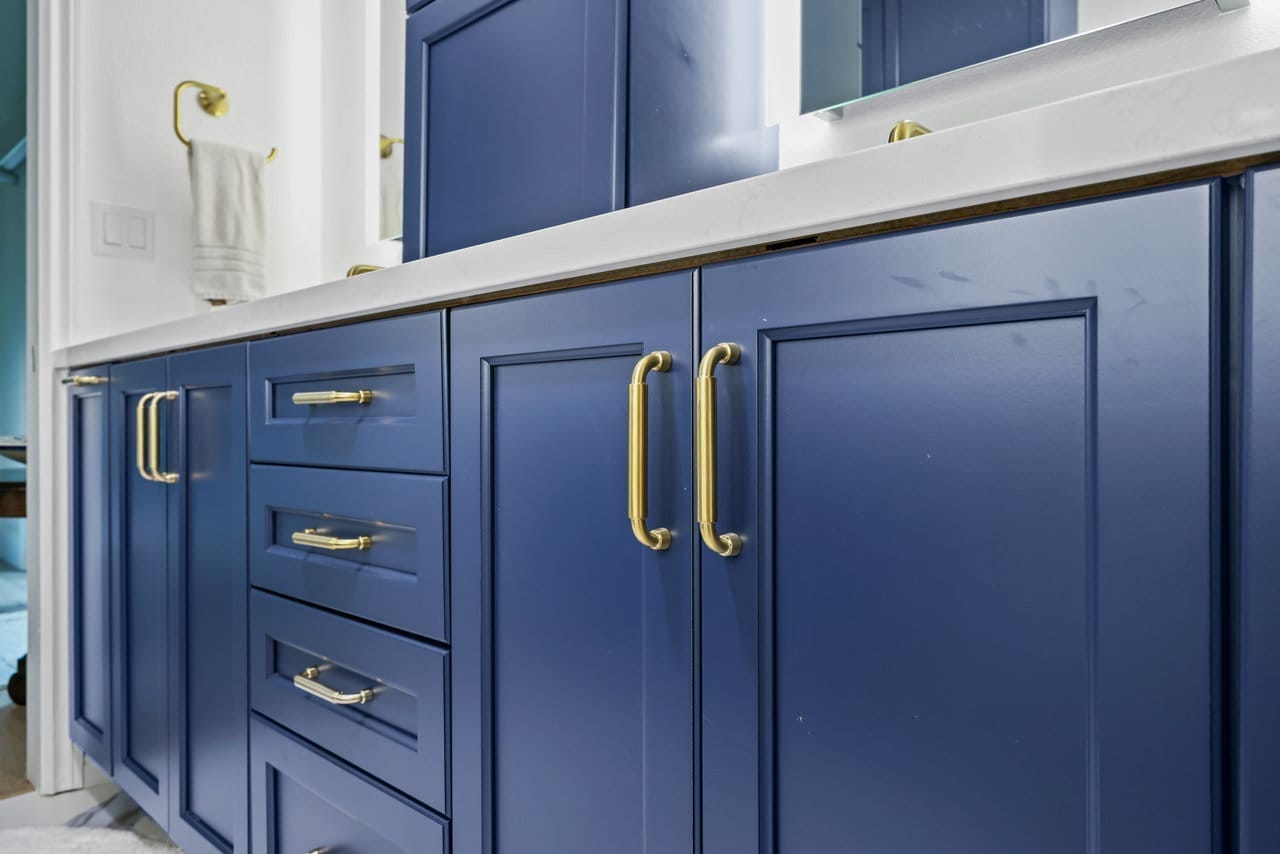close-up of navy raised-panel cabinet doors and drawers with elongated brass pulls