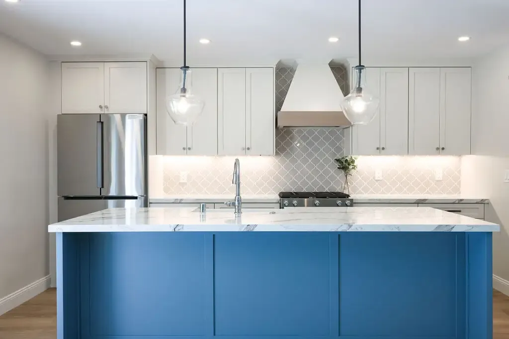 Contemporary kitchen with blue island, white cabinets and arabesque tile backsplash