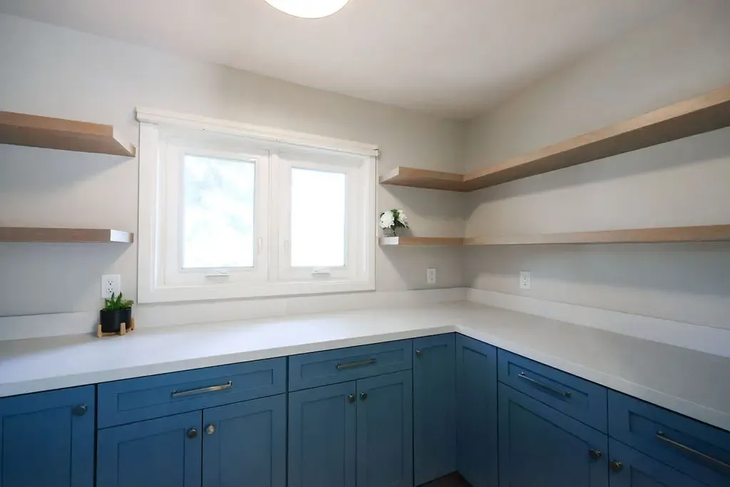 Corner pantry featuring navy base cabinets, light counters, and open oak shelving
