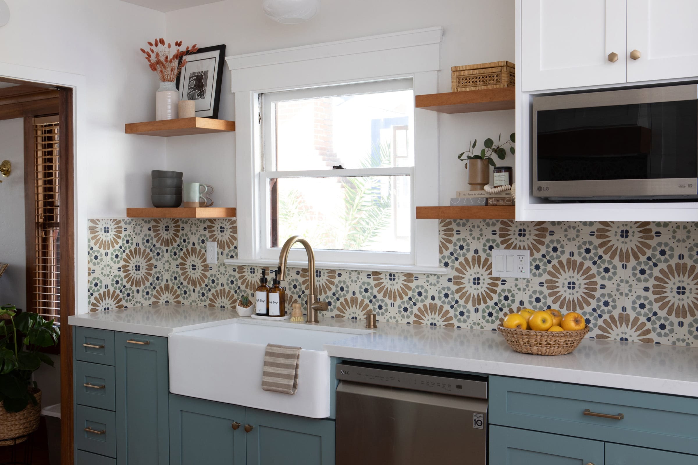 Cottage kitchen with teal cabinets, farmhouse sink and colorful patterned tile backsplash