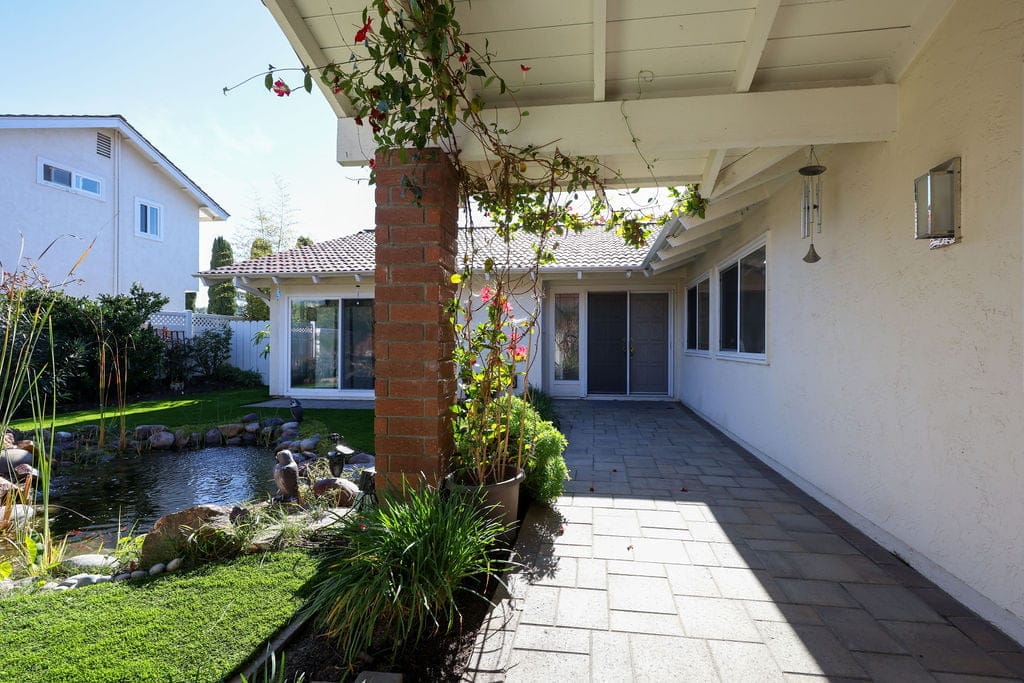Covered patio with brick column, koi pond and lush green landscaping