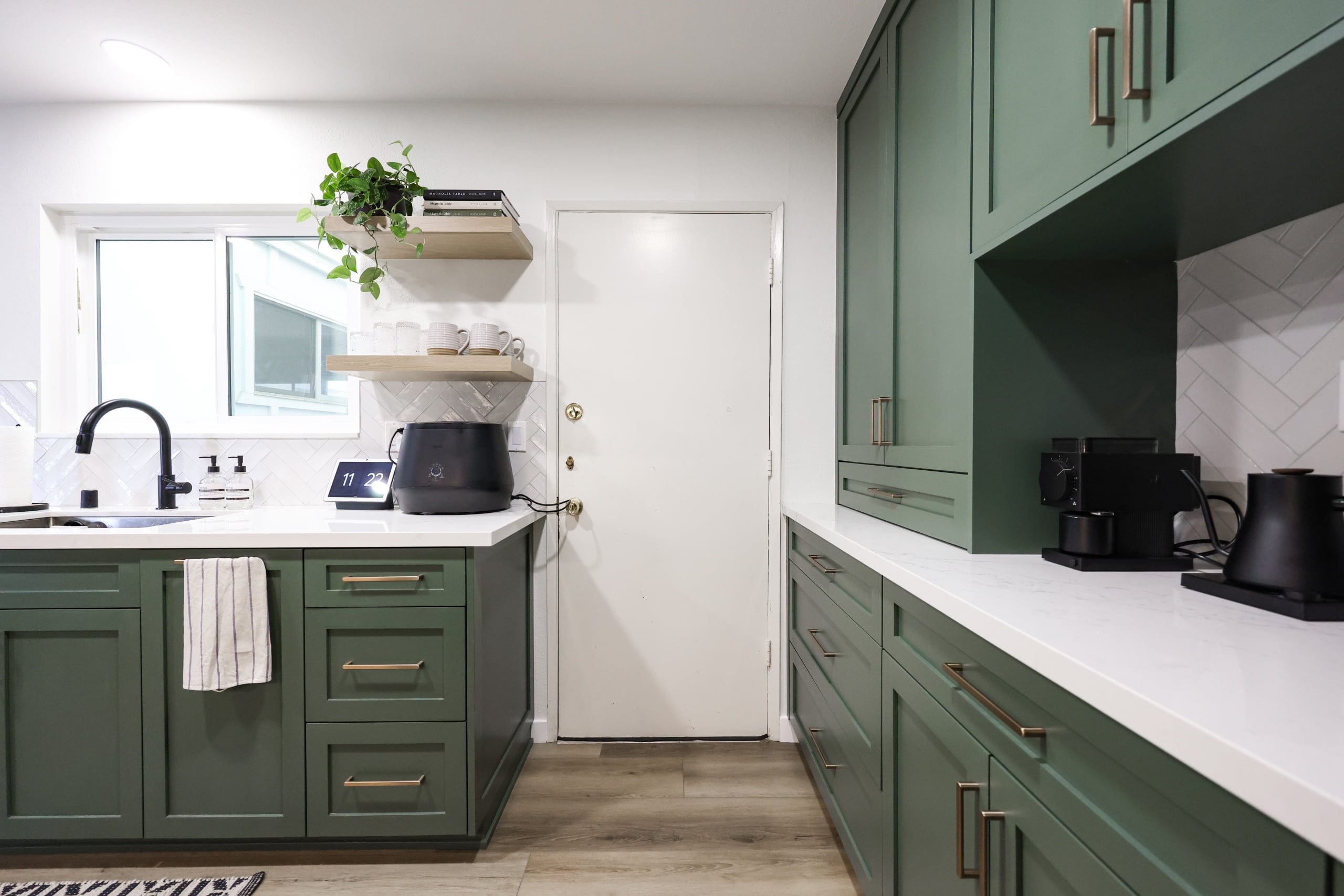 Dark green cabinetry with quartz counters, herringbone tile backsplash and matte black fixtures