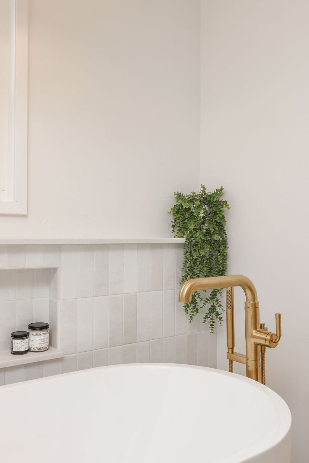 Detail of soaking tub niche with brass tub filler and stacked tile