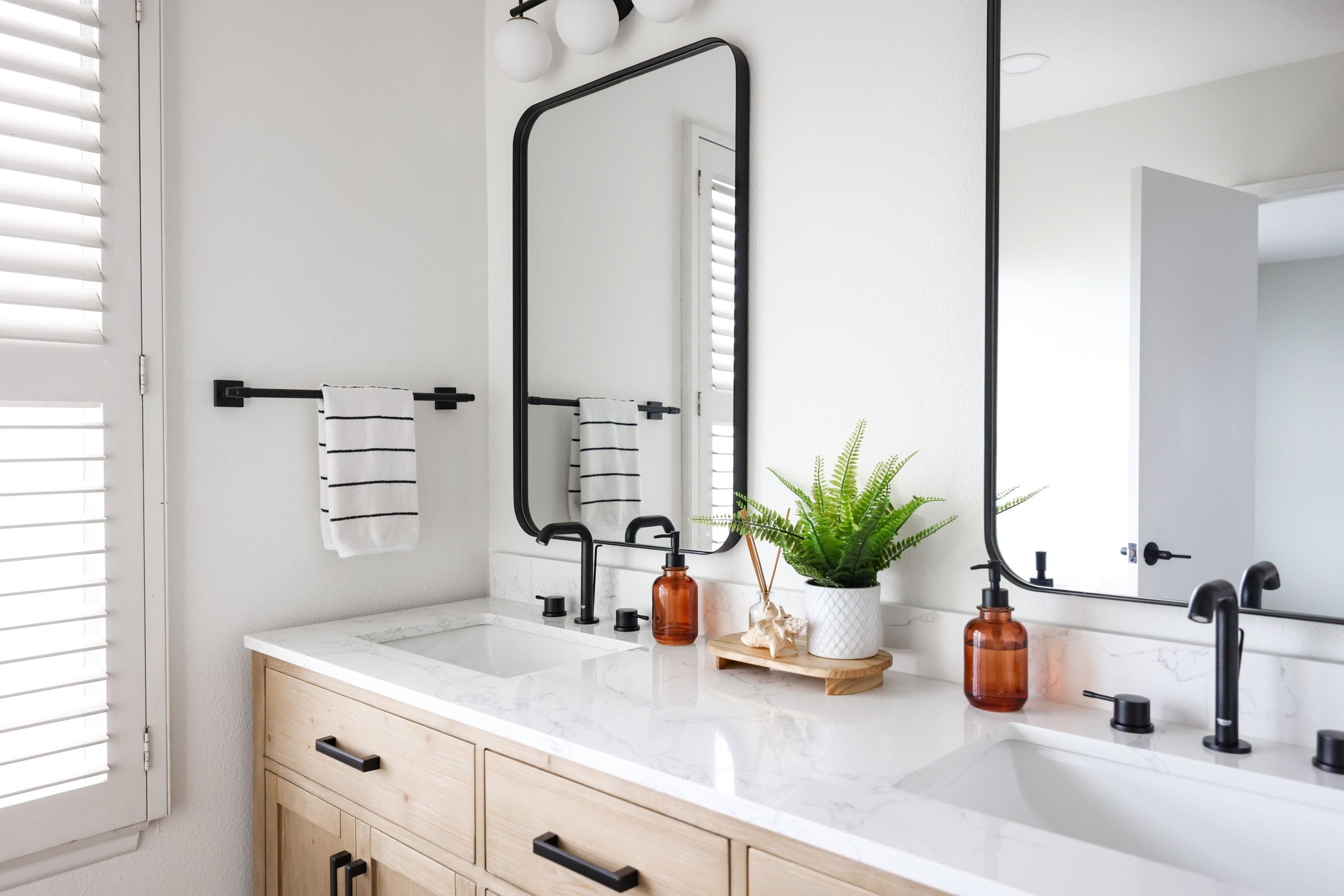 Double-sink bathroom vanity in oak with matte black faucets and marble counter