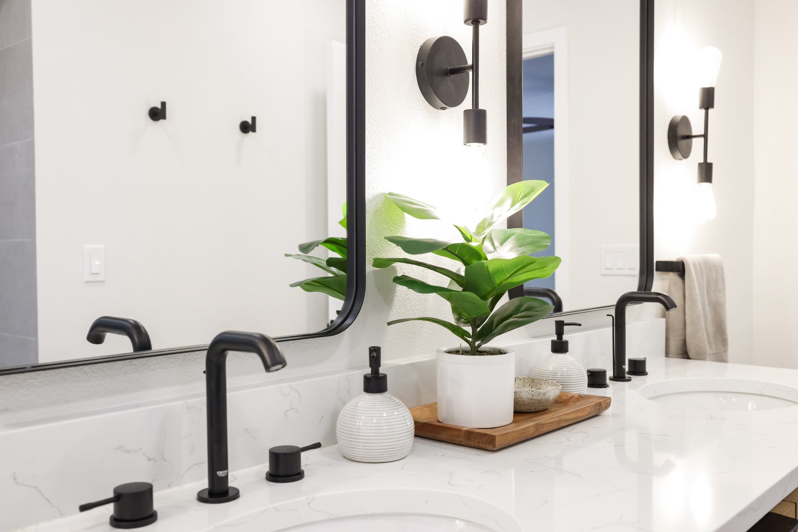 Double vanity detail with white quartz counter, black faucets and framed mirrors