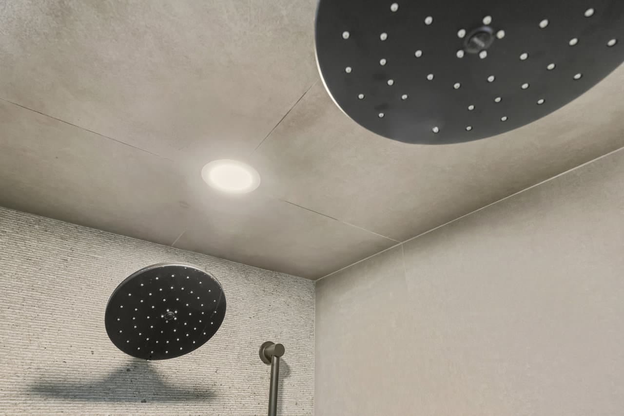 Dual ceiling and wall rainfall showerheads in gray tiled walk-in shower