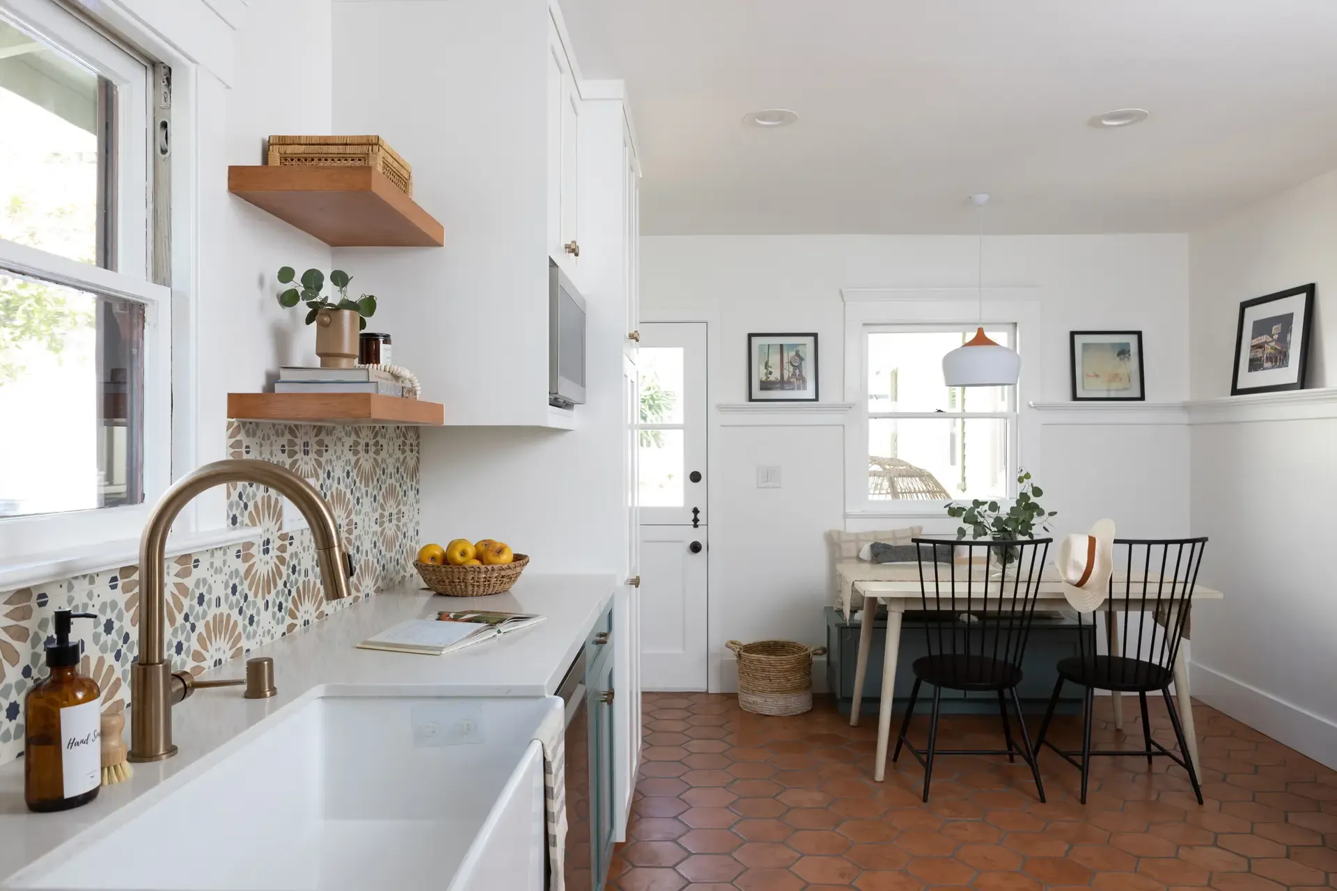 Farmhouse kitchen with apron sink, patterned tile, terracotta floor, and open shelving