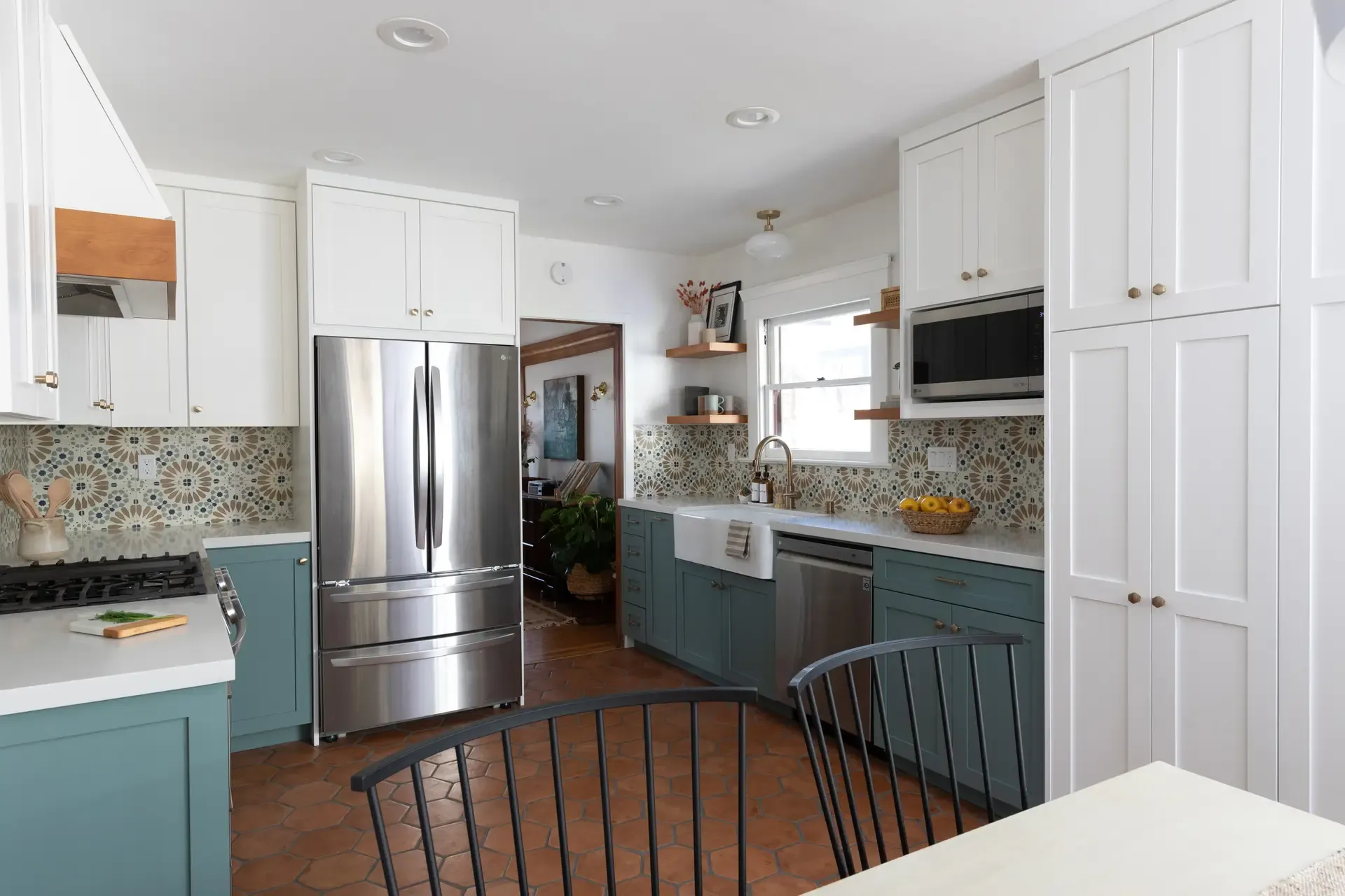 Galley kitchen remodel with teal cabinets, stainless appliances, and terracotta hexagon tile floor