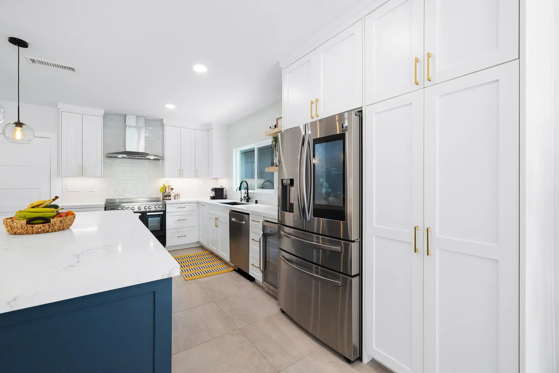 Galley kitchen with navy island, white cabinets and stainless French-door refrigerator