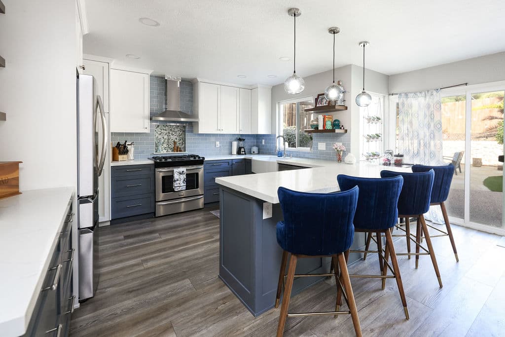 Galley kitchen with peninsula, blue velvet stools and wood-look plank flooring