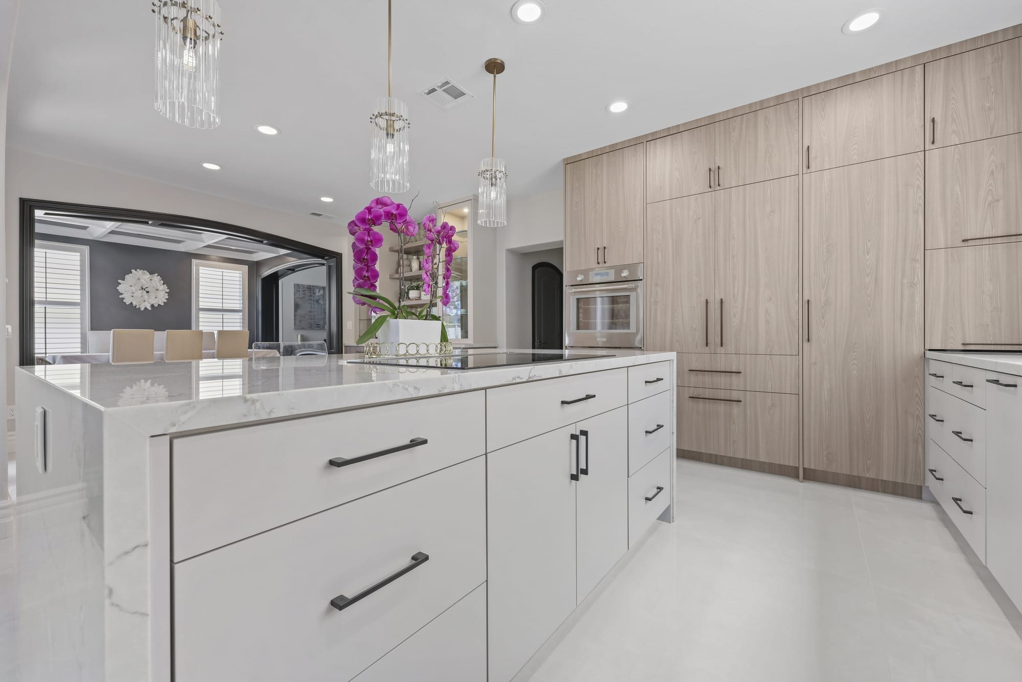 Modern kitchen island in white quartz with light oak cabinetry and crystal pendant lights