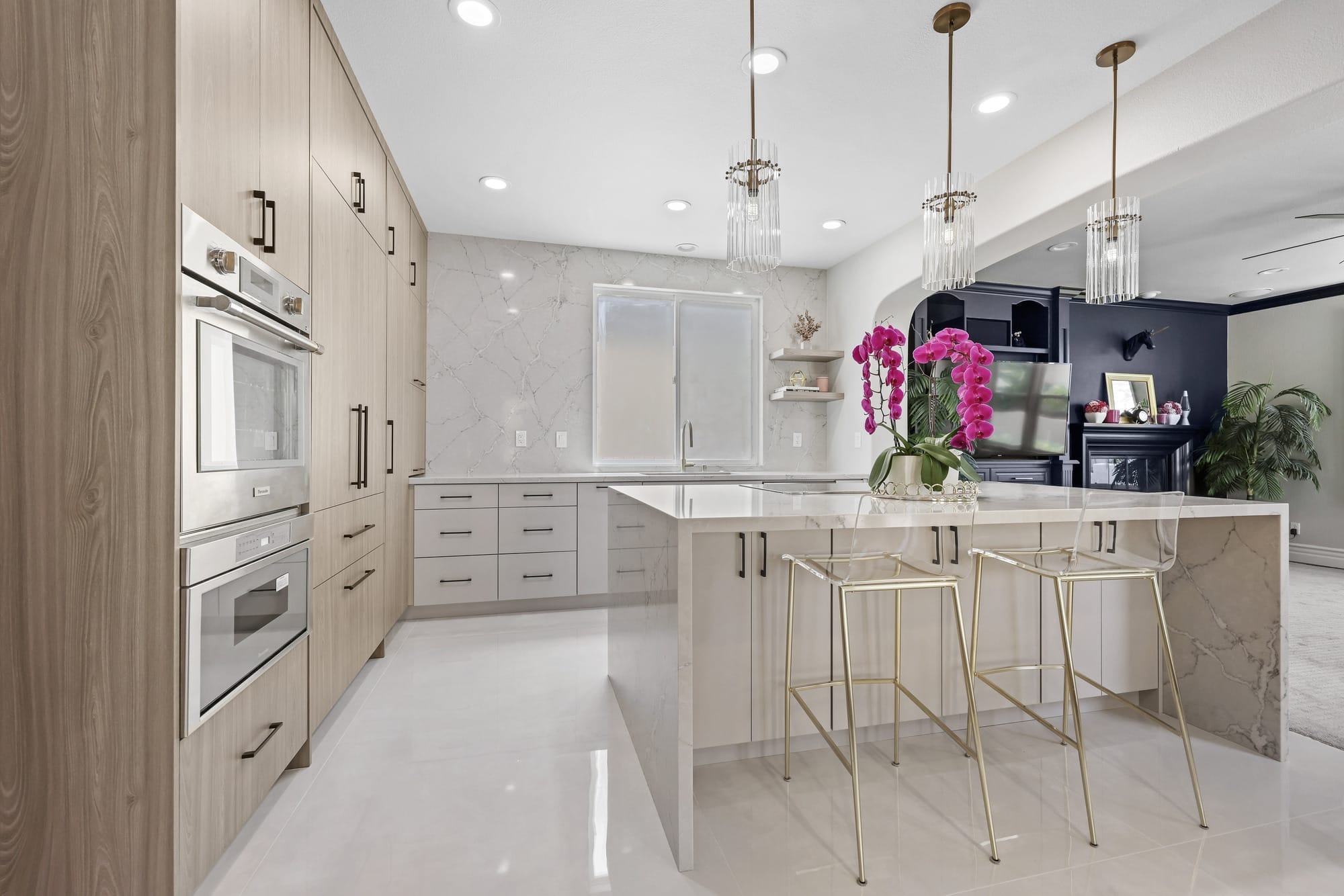 Open-concept kitchen with two-tone oak and gray cabinetry and gold barstools at island