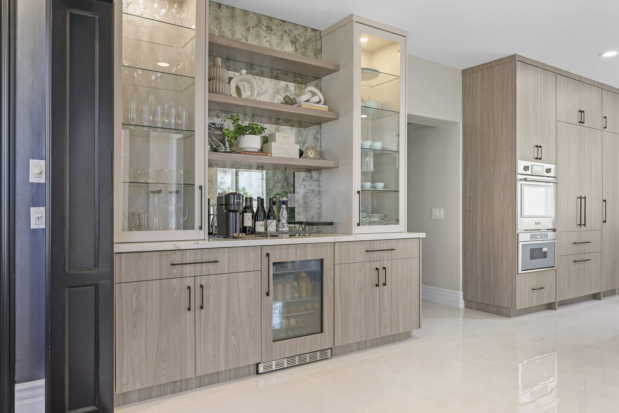 Built-in beverage bar with oak cabinets, glass display shelving and wine fridge