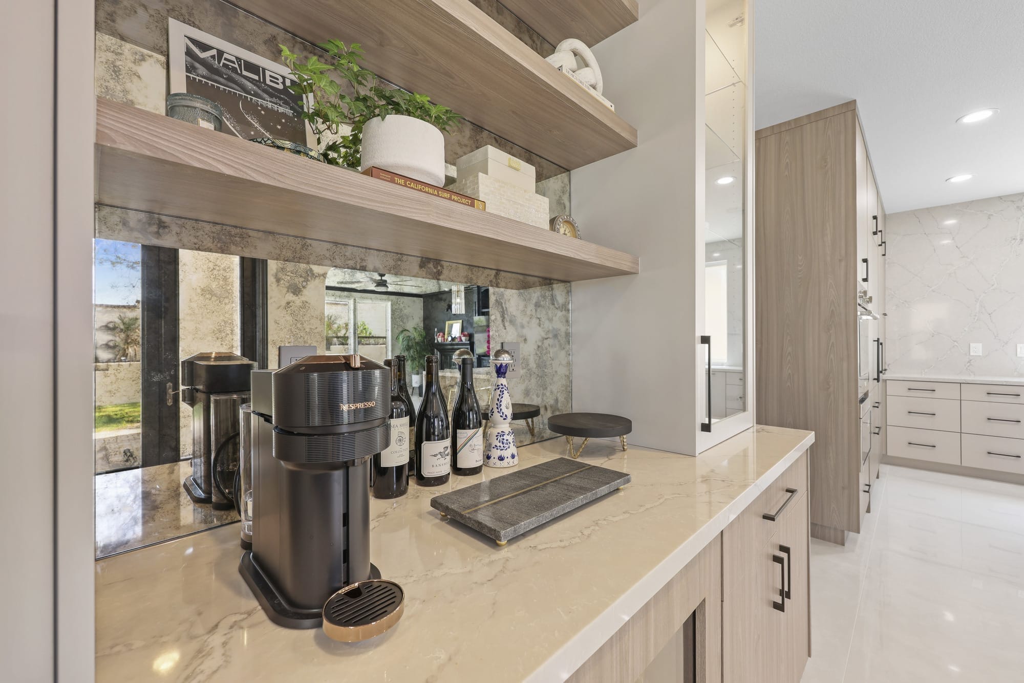 Butler pantry bar with Nespresso machine, oak shelves and antiqued mirror backsplash