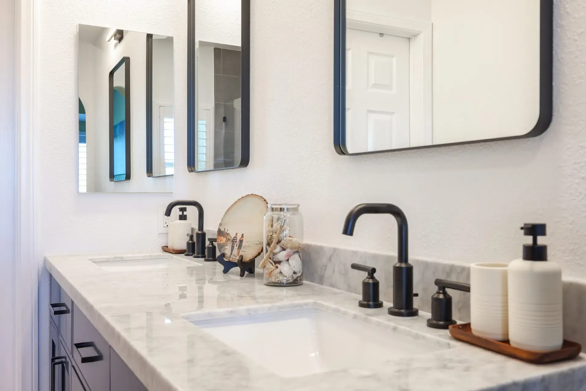 Gray double vanity with marble top, black faucets, and framed mirrors