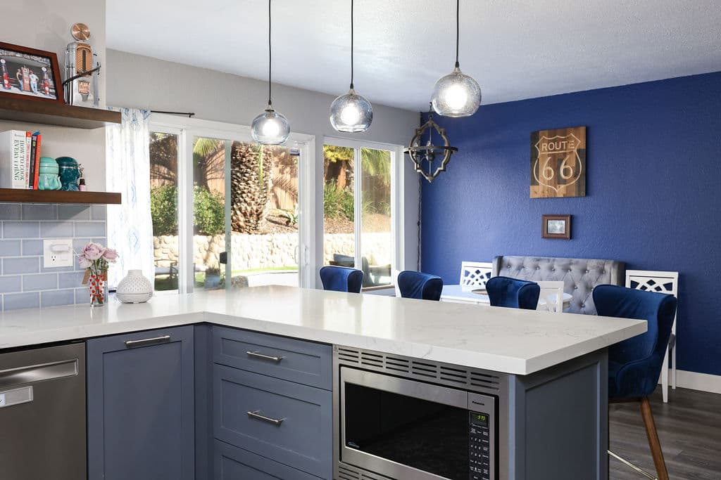 Gray island with built-in microwave beside dining nook and bold cobalt accent wall