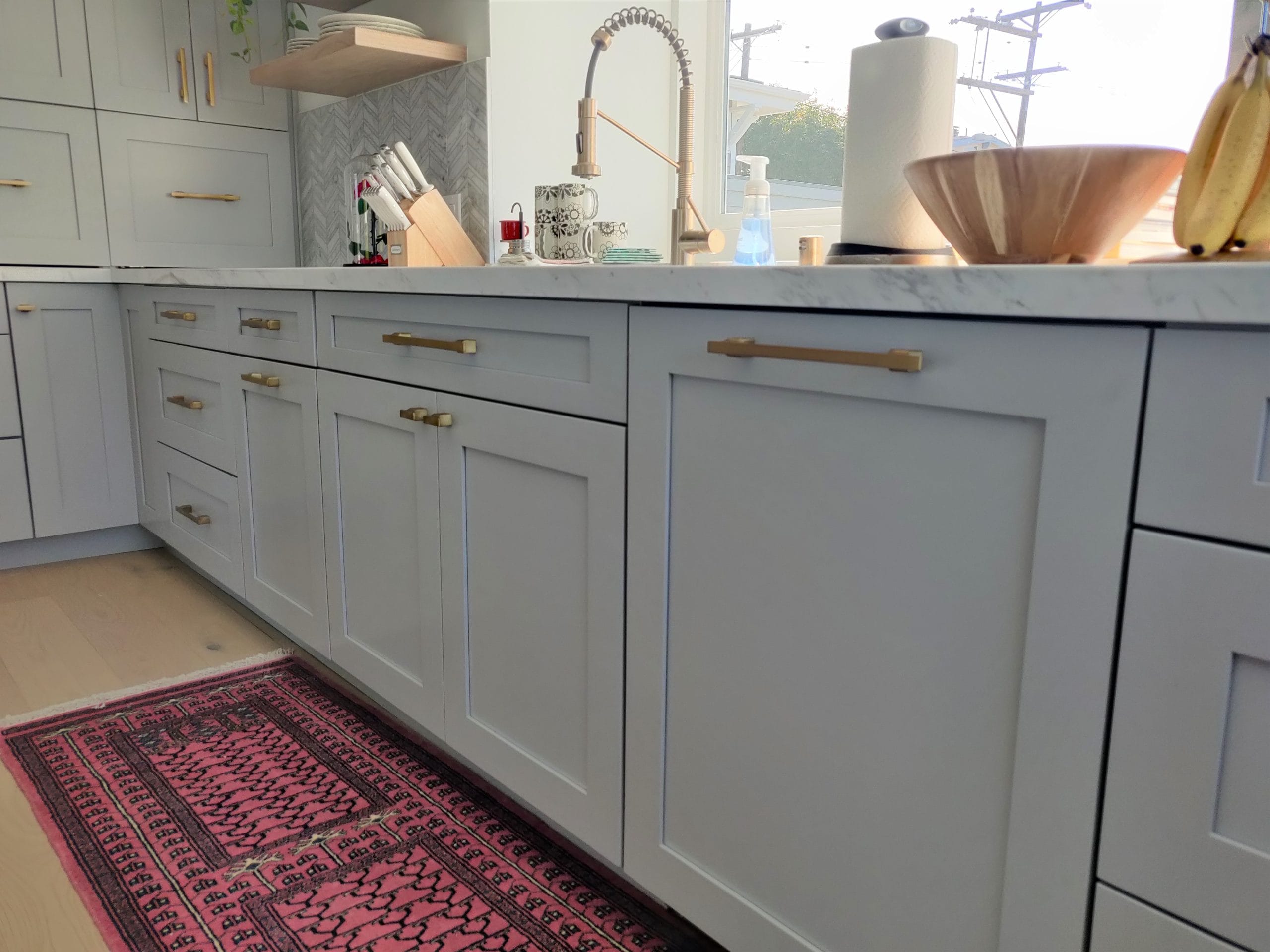 gray shaker base cabinets with brass pulls, marble counter, and red runner rug