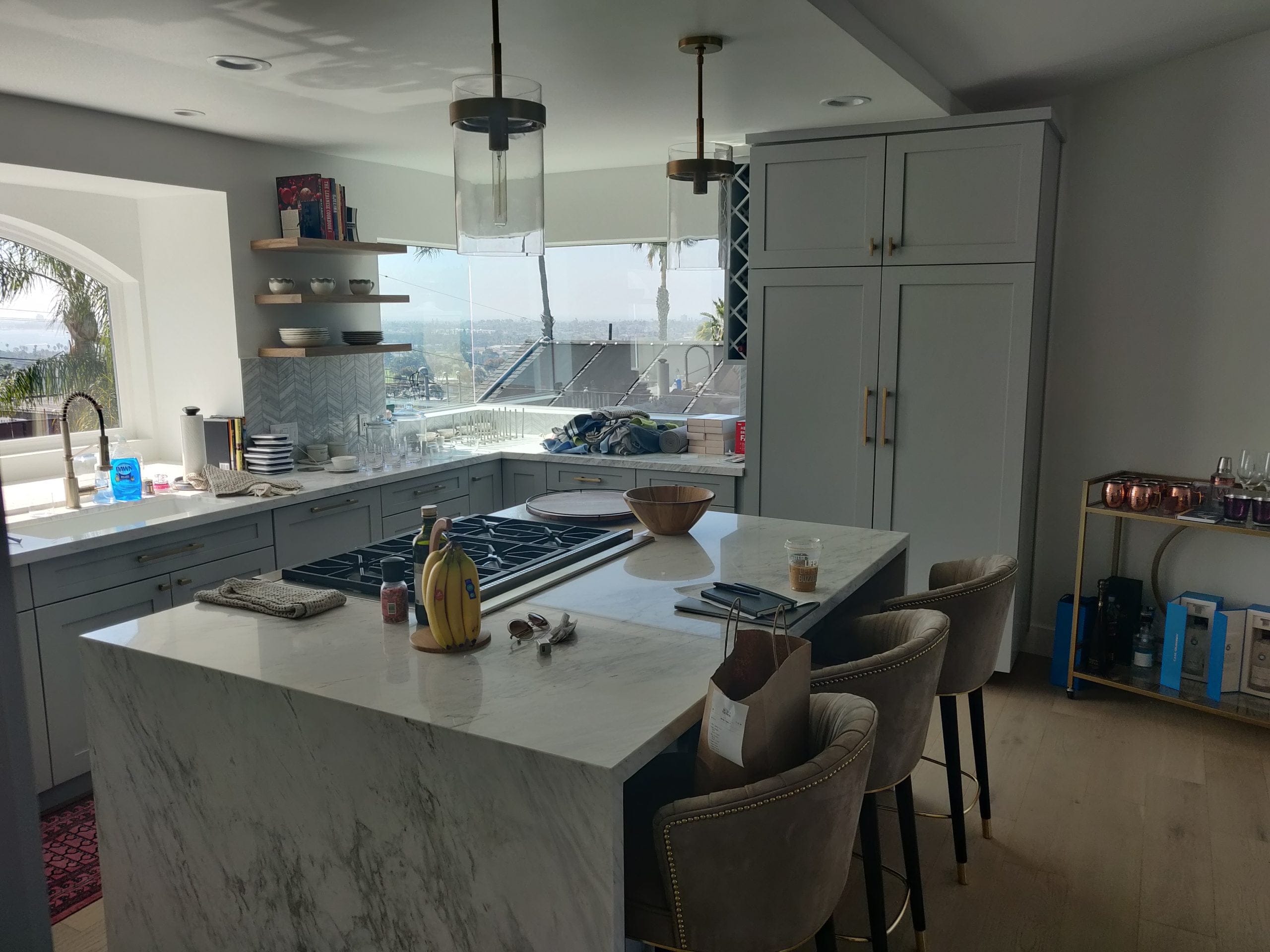 gray shaker kitchen with marble waterfall island and panoramic city-view windows