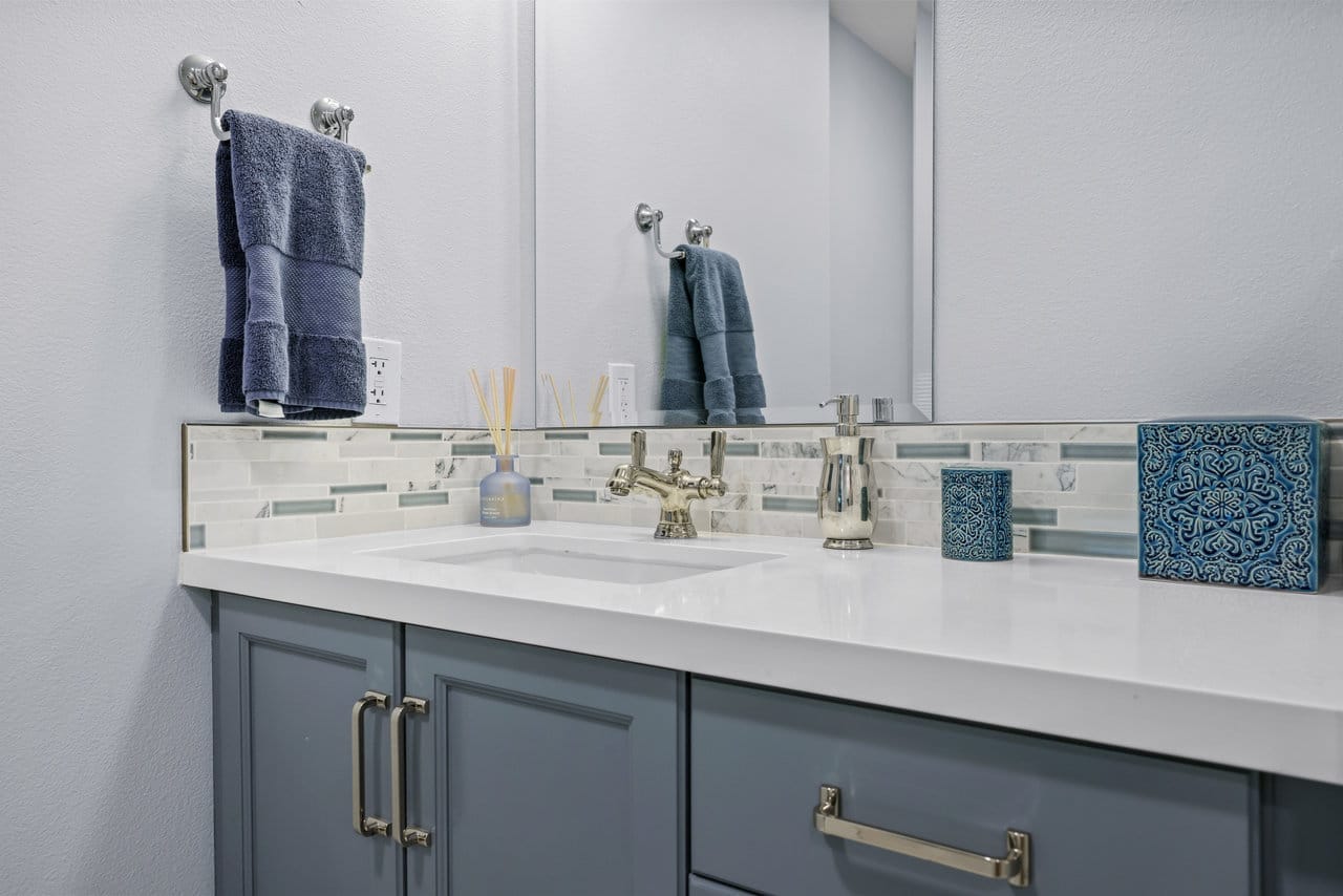 gray shaker vanity with quartz counter, mixed marble tile backsplash and polished nickel faucet