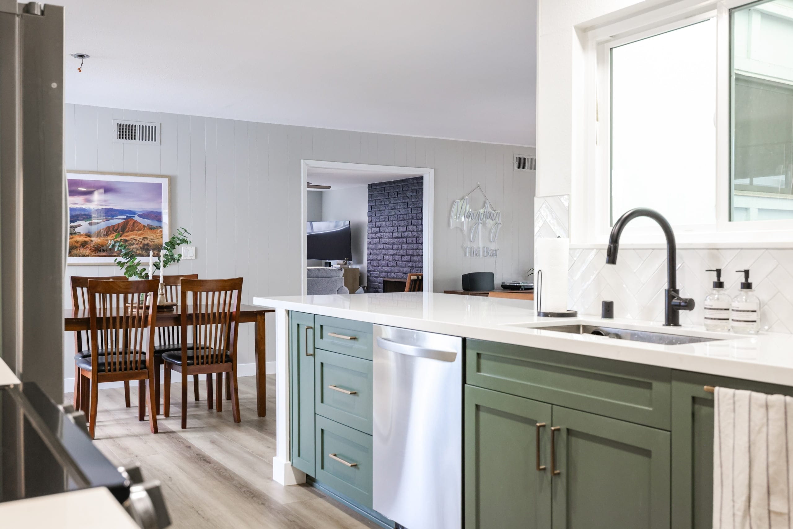 Green island with quartz waterfall counter, stainless dishwasher and matte black gooseneck faucet
