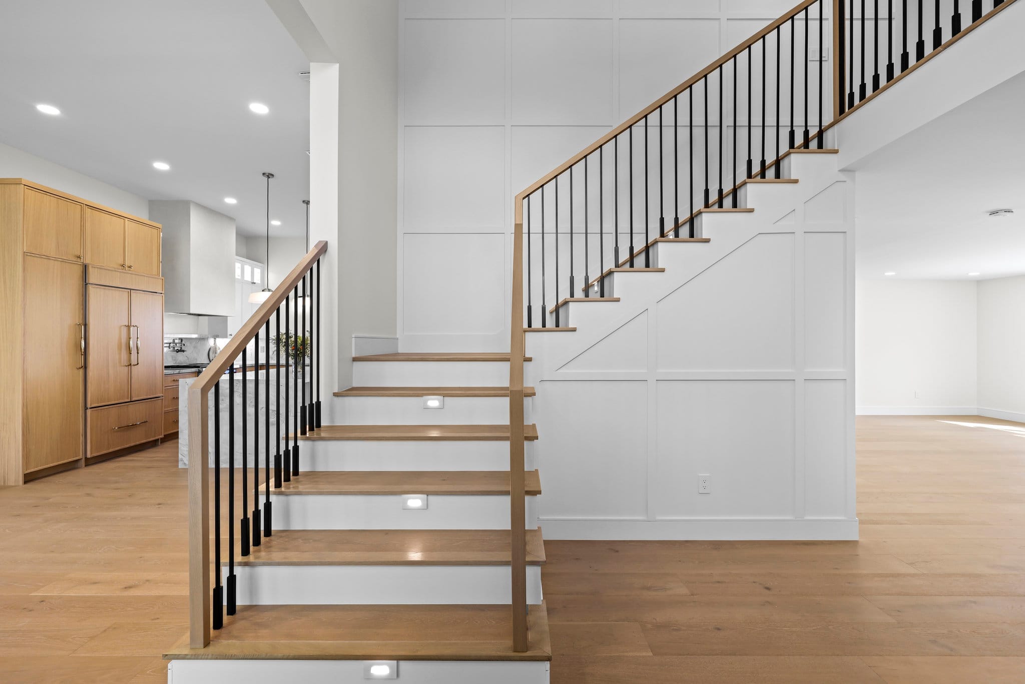 Open staircase with oak treads, black metal balusters and white board-and-batten wall