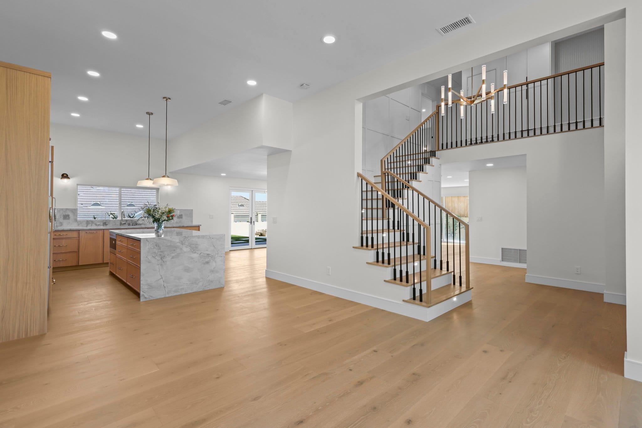 Open-concept great room with marble kitchen island and curved wood staircase