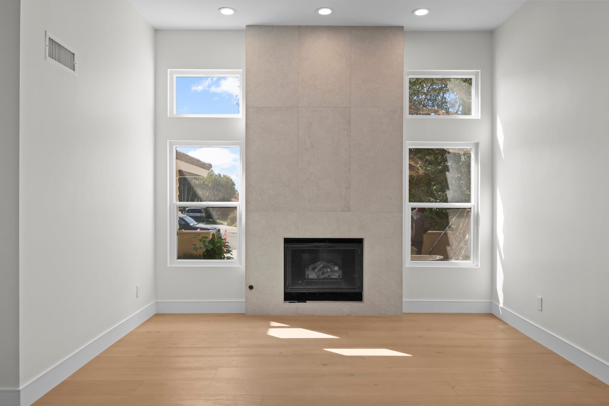 Bright living room with floor-to-ceiling gray tile fireplace surround and oak flooring