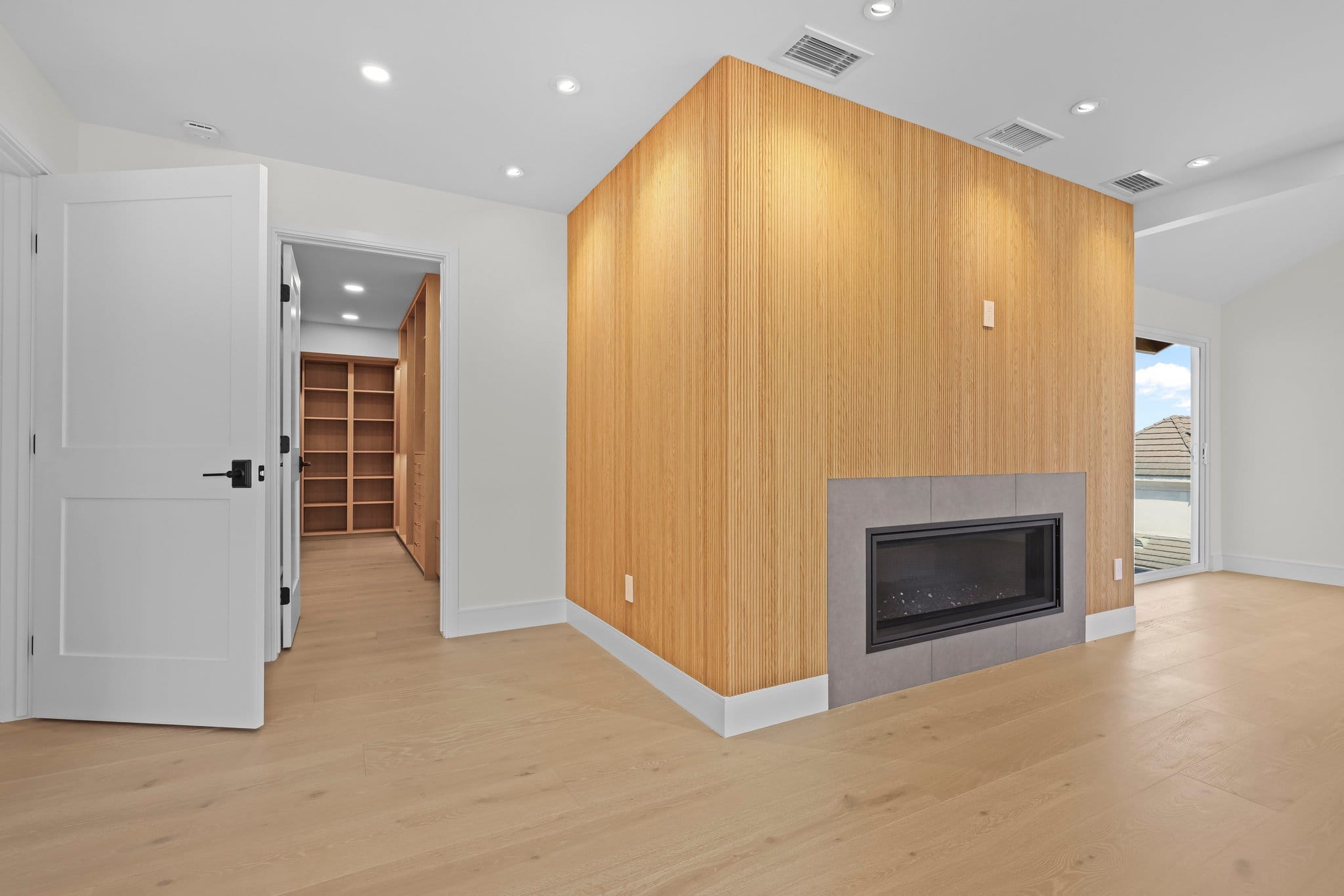 Living room with vertical oak-clad fireplace volume, gray tile hearth and sliding glass door