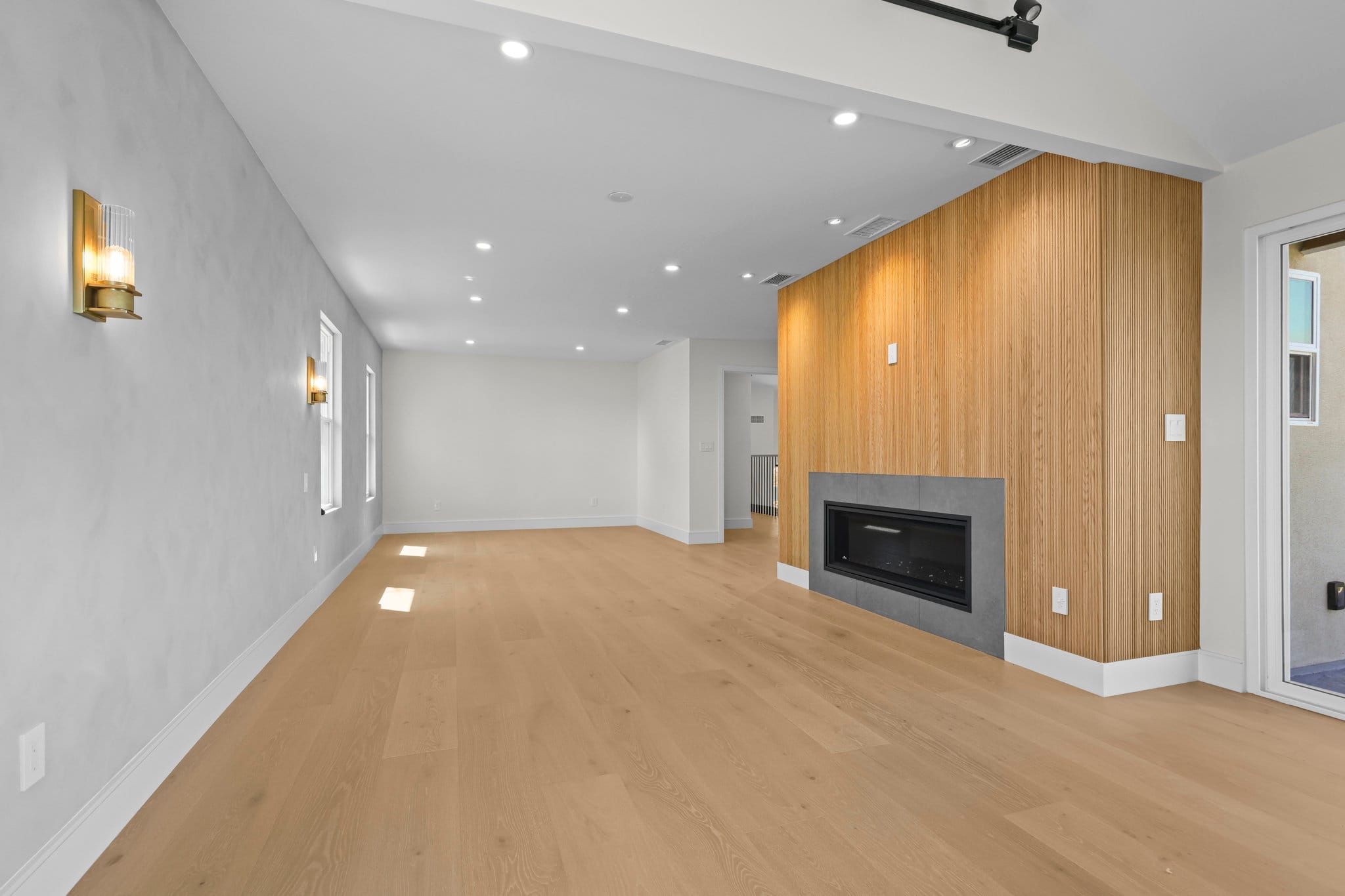 Open living space with white oak slatted fireplace wall and warm wood flooring
