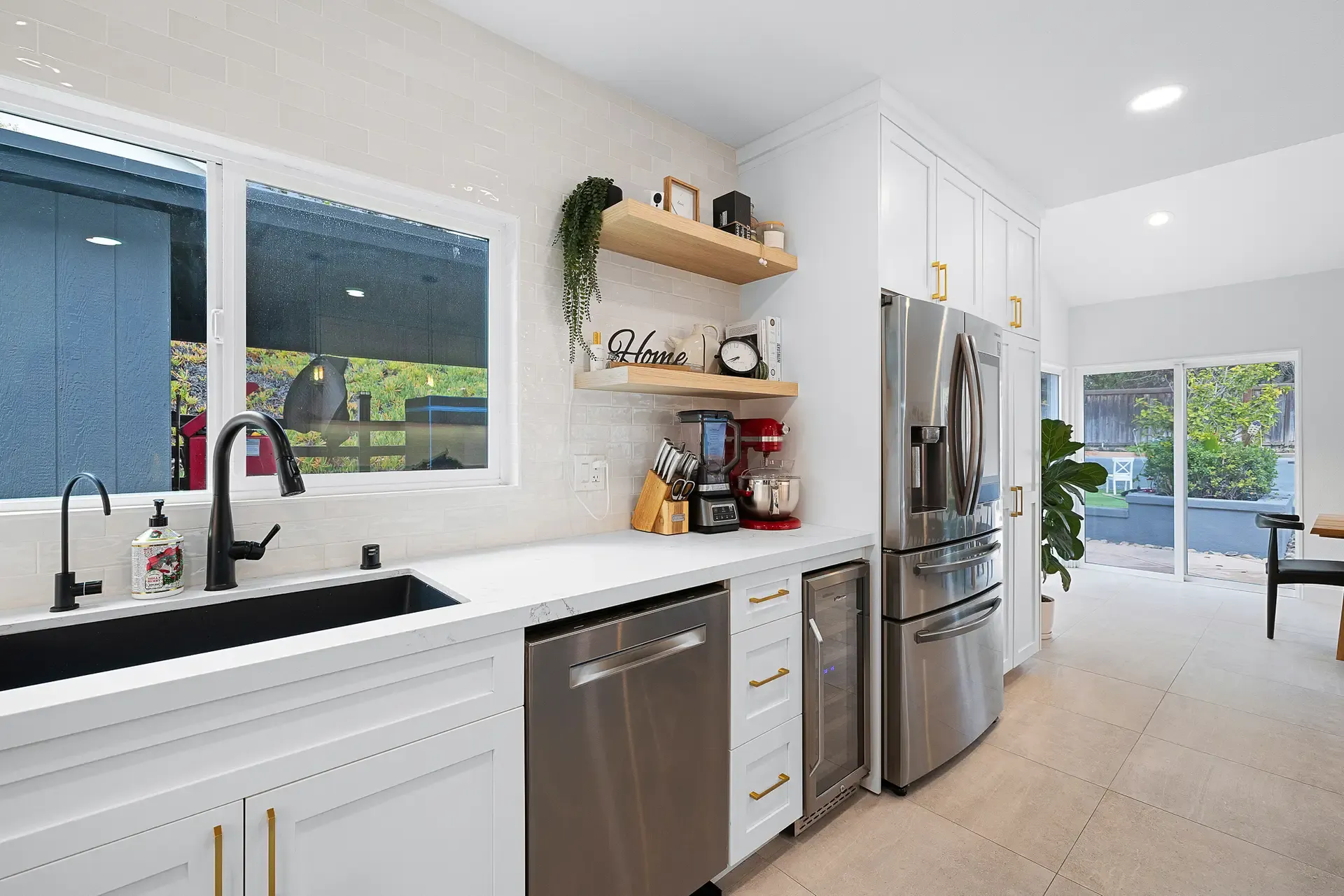 Kitchen corner with white cabinets, stainless dishwasher and counter-depth refrigerator