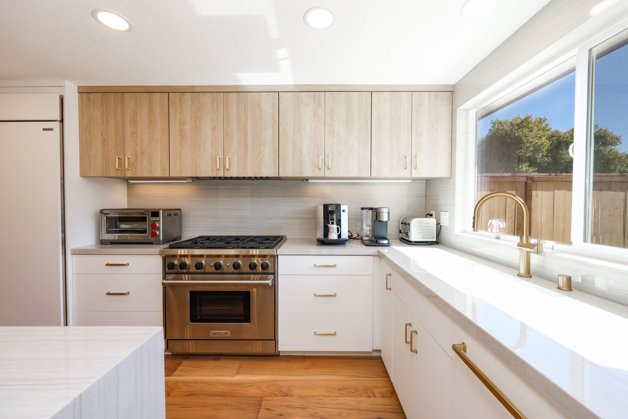 Kitchen run with stainless gas range, oak uppers and brass farmhouse faucet