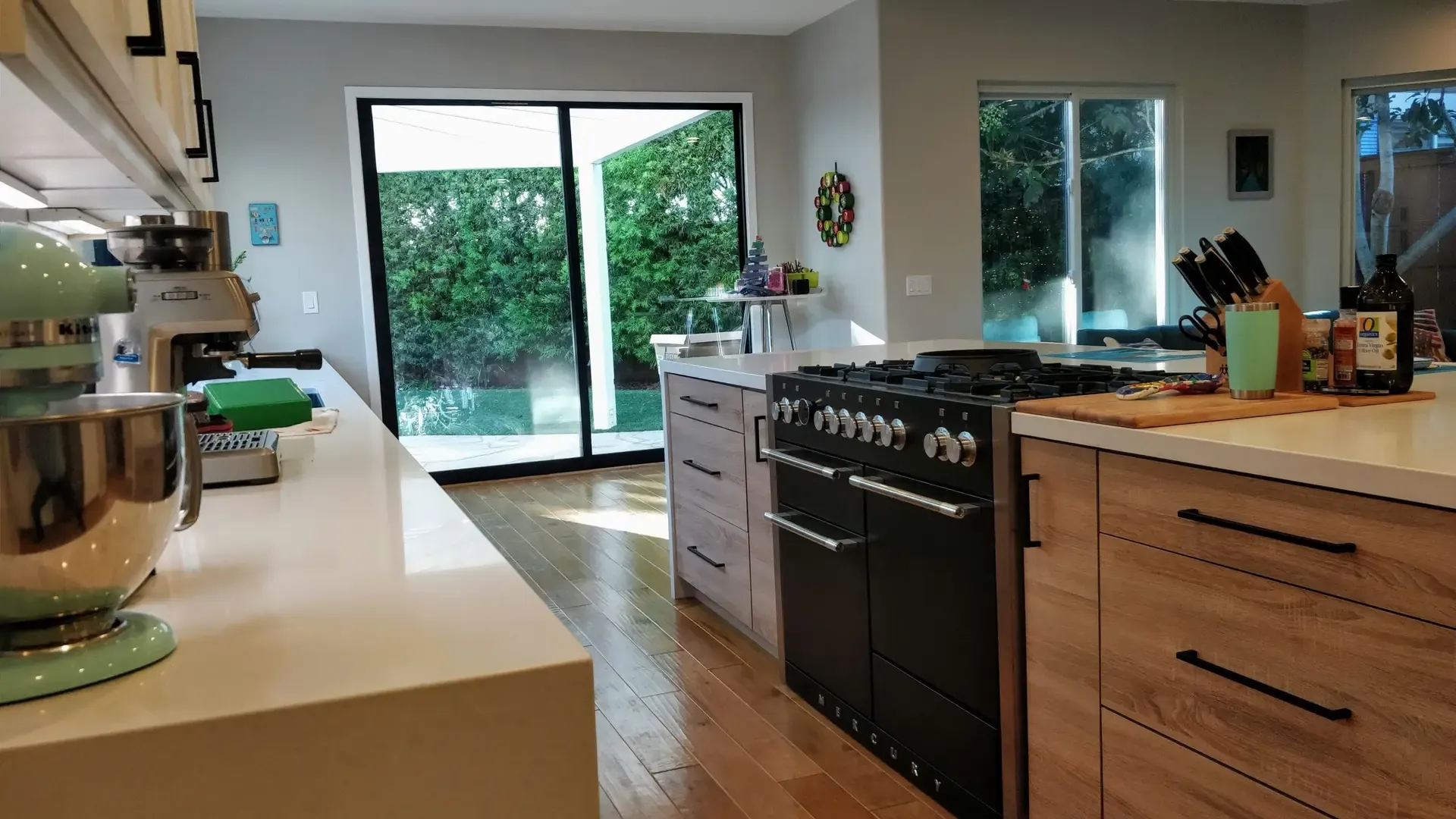 Kitchen with black range, wood cabinetry and sliding glass doors to backyard