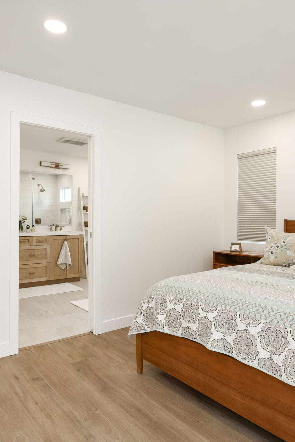 Light-filled bedroom with wood floors and open ensuite bathroom view