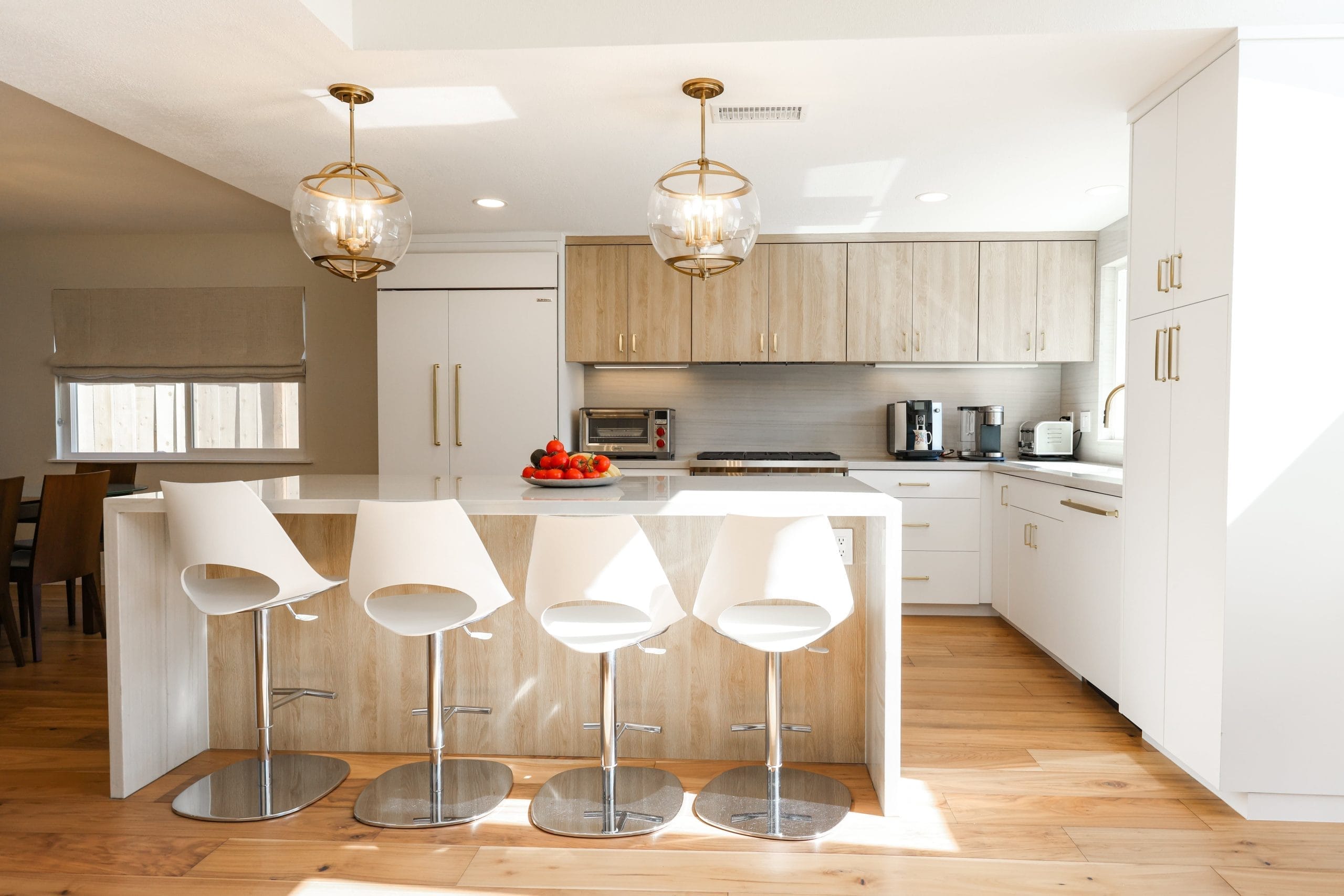 Light wood kitchen with white quartz island, bar stools, and brass pendant lighting
