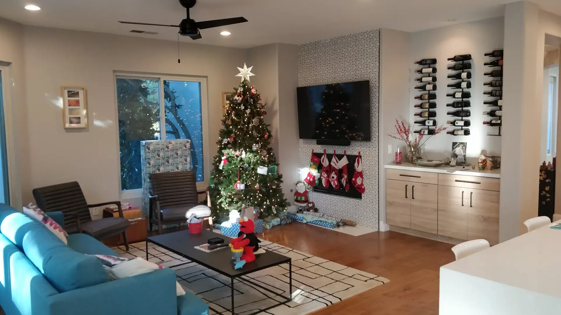 Living room with blue sofa, wood floors, wine display and decorated Christmas tree