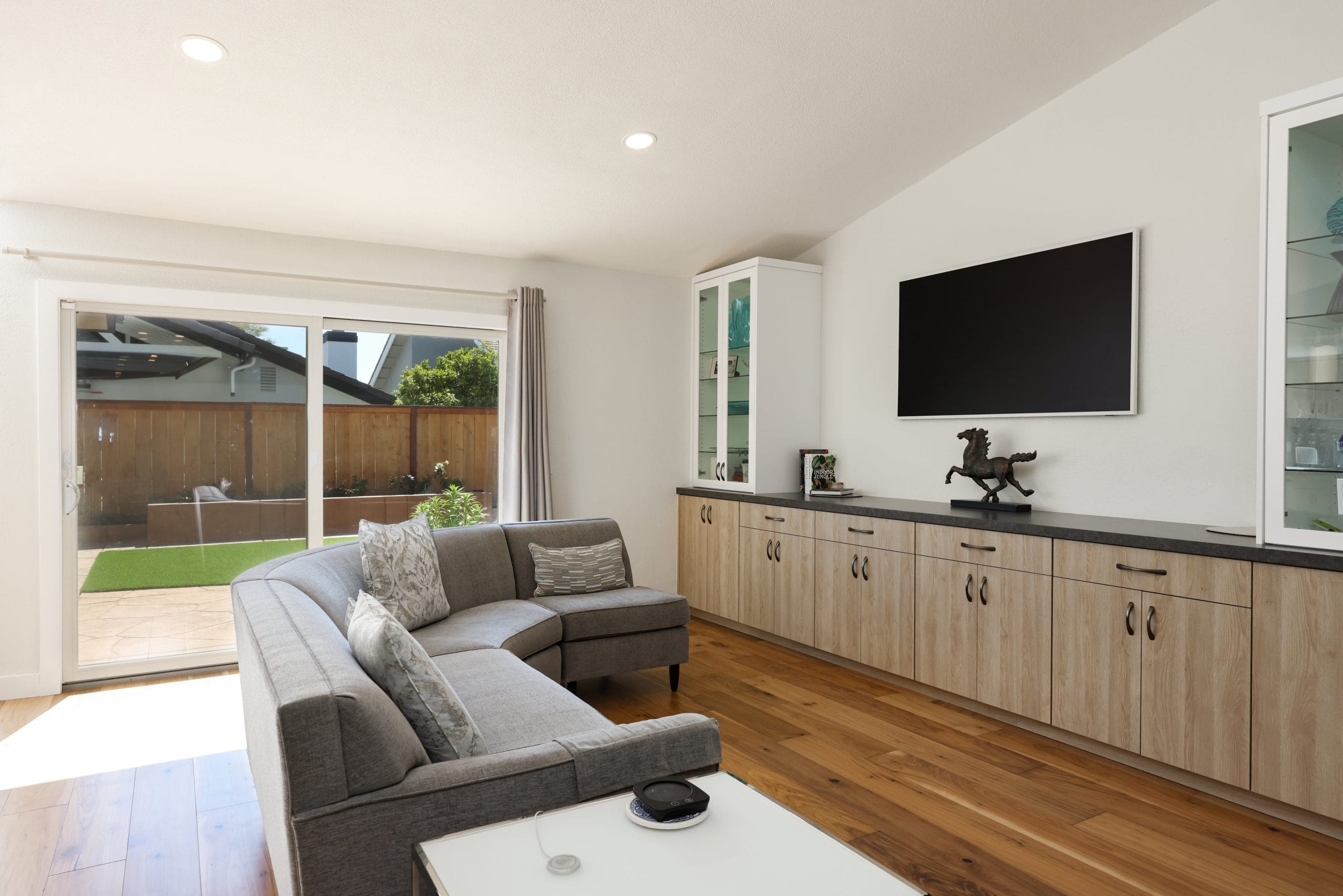 Living space with sectional sofa, oak cabinetry and backyard sliding glass door