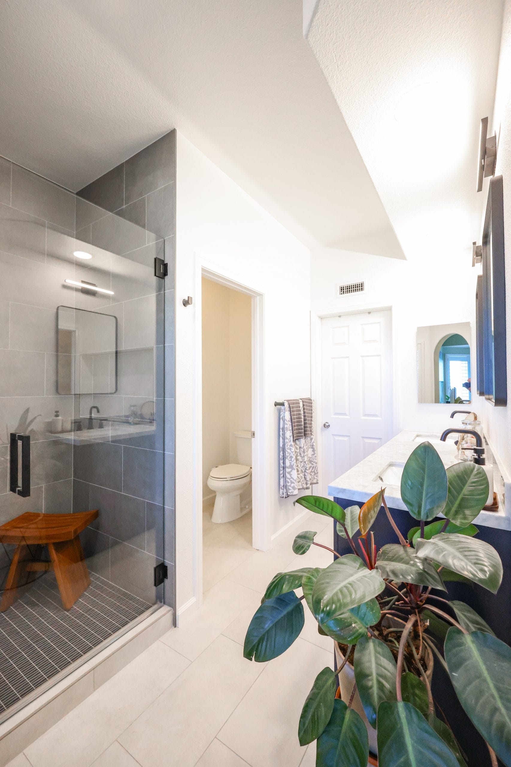 Long primary bath with glass shower, separate toilet room and double marble vanity