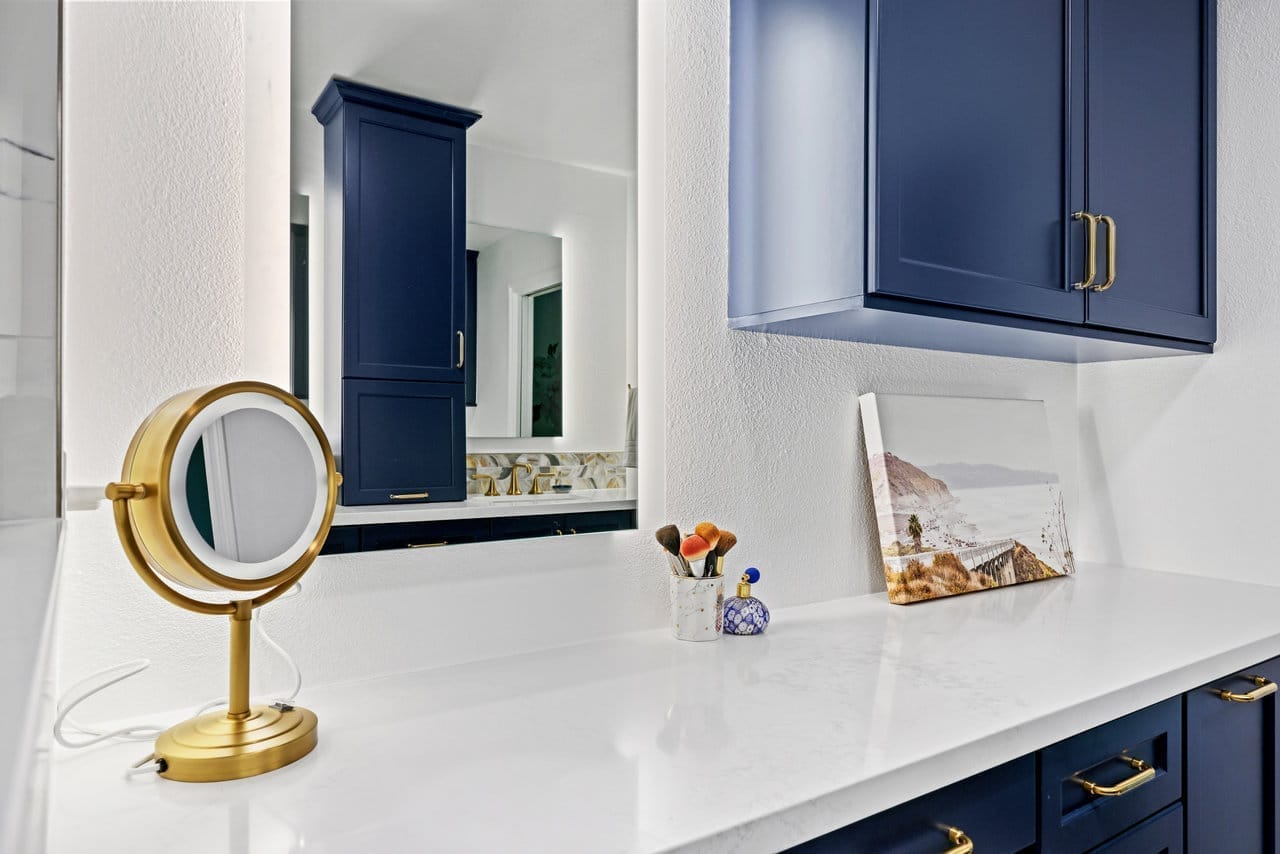 makeup vanity nook with navy upper cabinets, brass hardware and bright quartz countertop