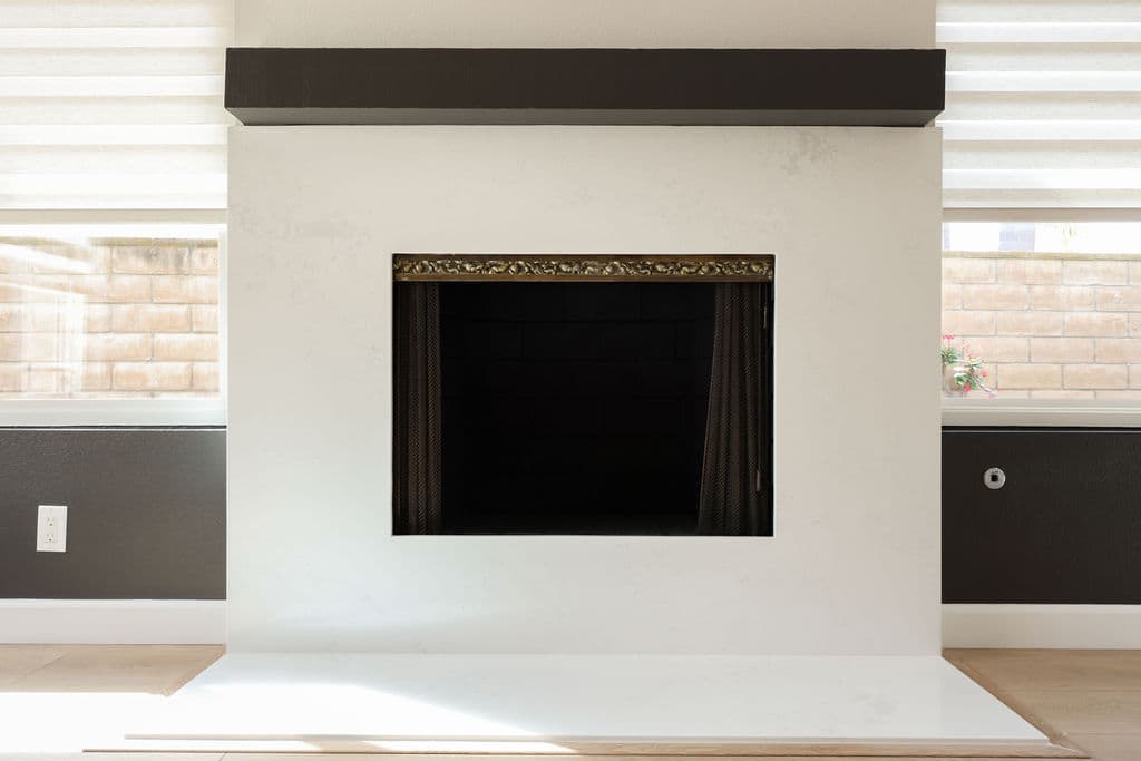 Minimalist white plaster fireplace surround with dark floating mantel and gray accents