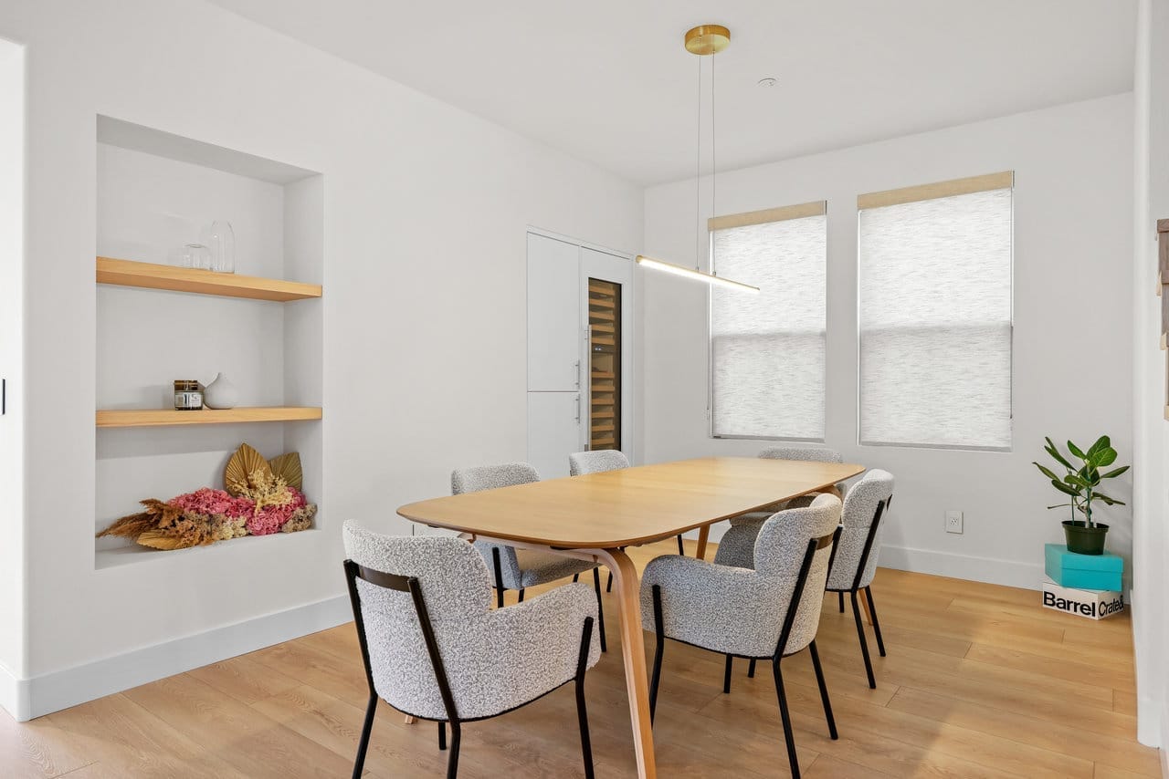 Bright dining room with oak table, boucle chairs, and recessed wood floating shelves