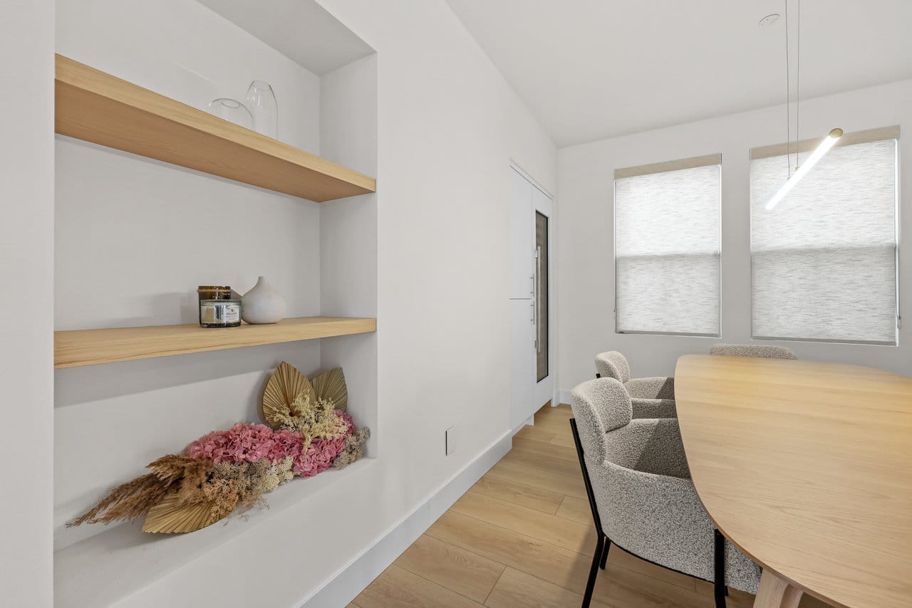 breakfast nook with floating wood shelves, oval table, boucle chairs, and oak flooring