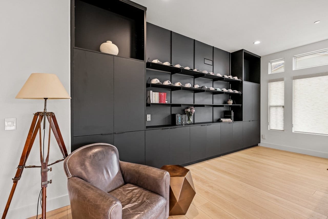 Living room with matte black built-in shelving, leather club chair and oak flooring