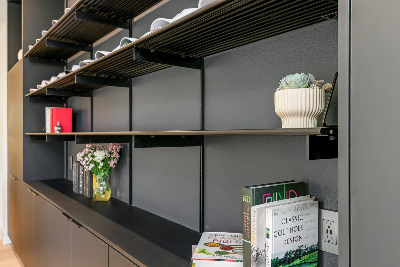Detail of matte black floating shelves styled with books, succulents, and fresh flowers