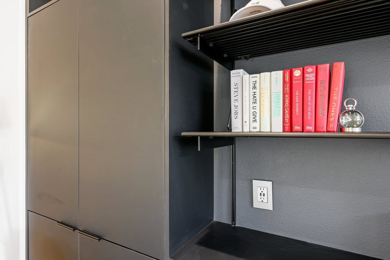 Black built-in bookshelf detail with floating shelf, books and dark cabinet doors